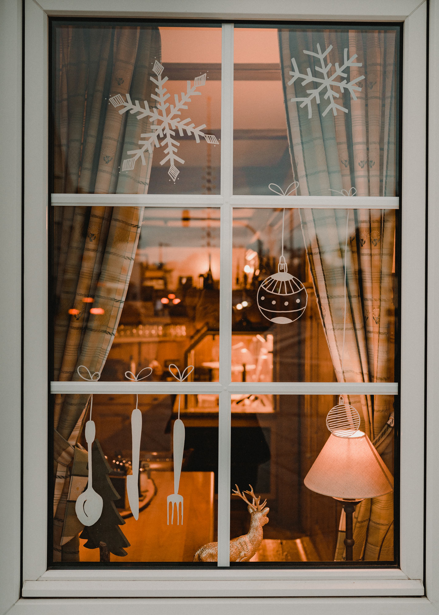 Gasthausfenster mit weißer Bemalung: Besteck, Schneeflocken und Christbaumkugeln.