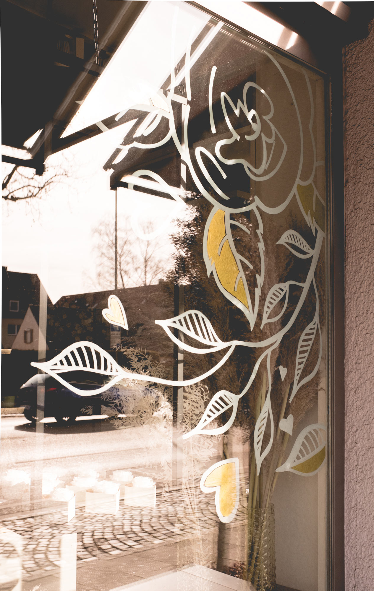 Eine auf das Schaufenster gezeichnete Rose mit Blättern und Herzen