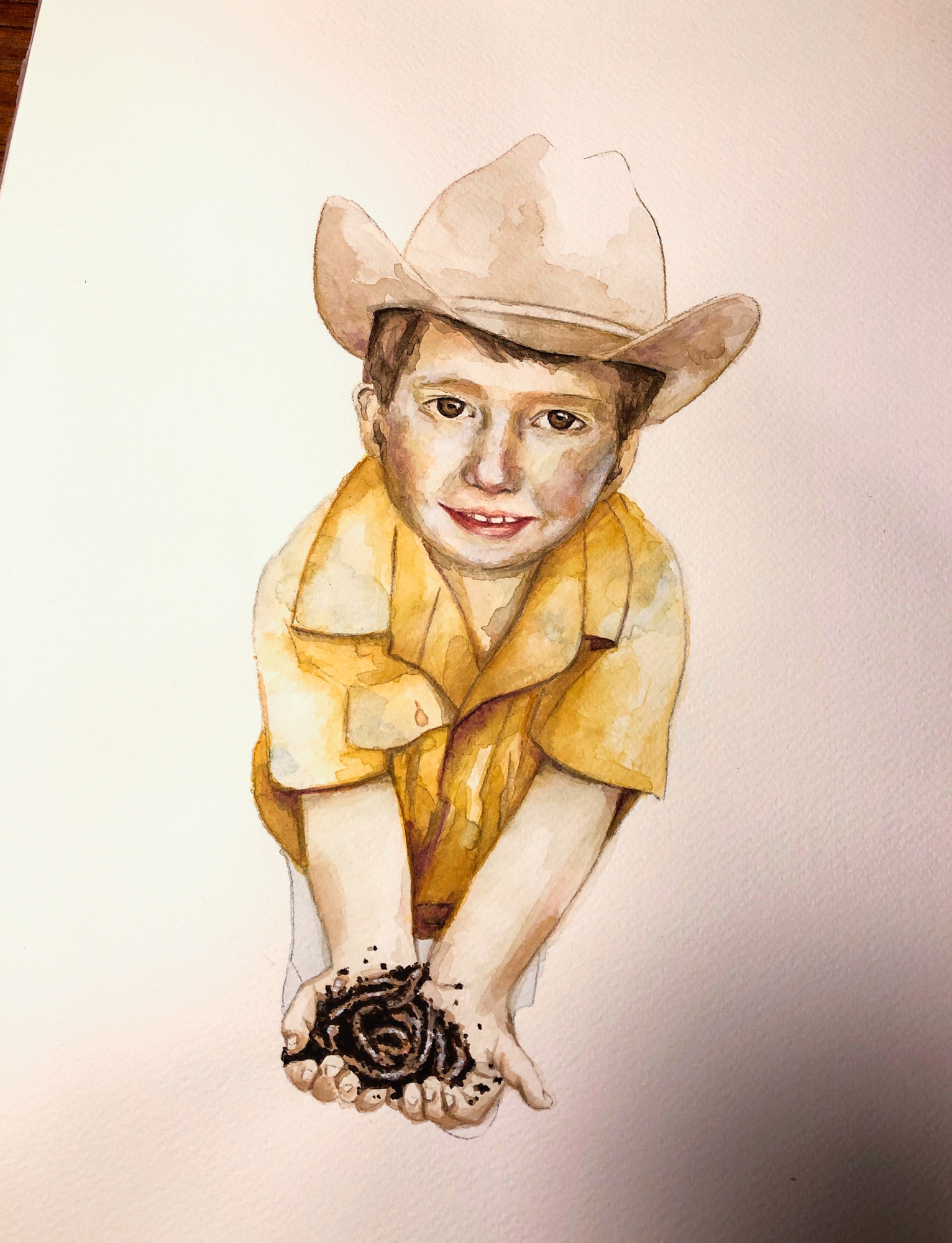 Zu sehen ist ein Aquarell-Porträt eines kleinenJungen mit Cowboyhut und gelben Hemd. Erhält Regenwürmer in den Händen und guckt den Betrachter direkt an.