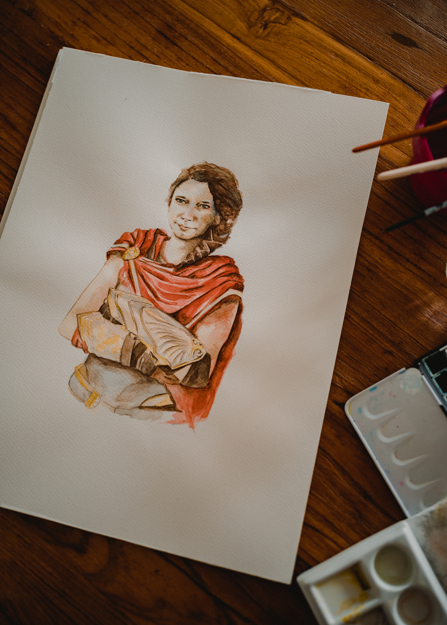 Das Foto zeigt ein Aquarell-Porträt einer jungen Frau im Kostüm der griechischen Heldin aus dem Computerspiel 