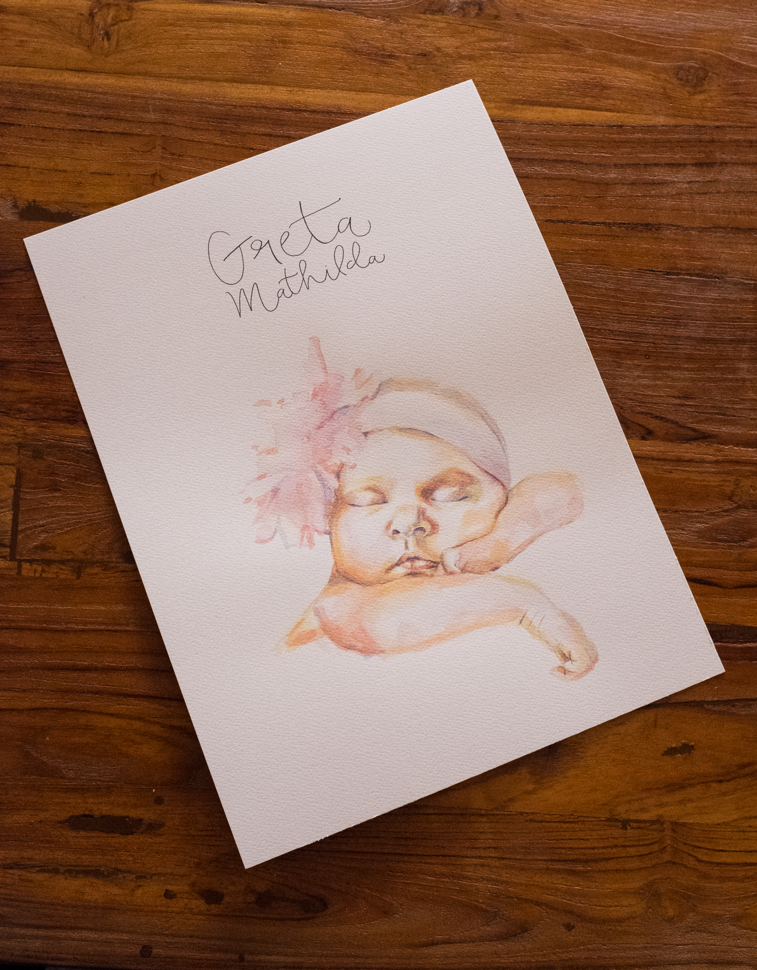 Ein Babyporträt mi Aquarelltechnik gemalt und dem Namen in Handschrift.